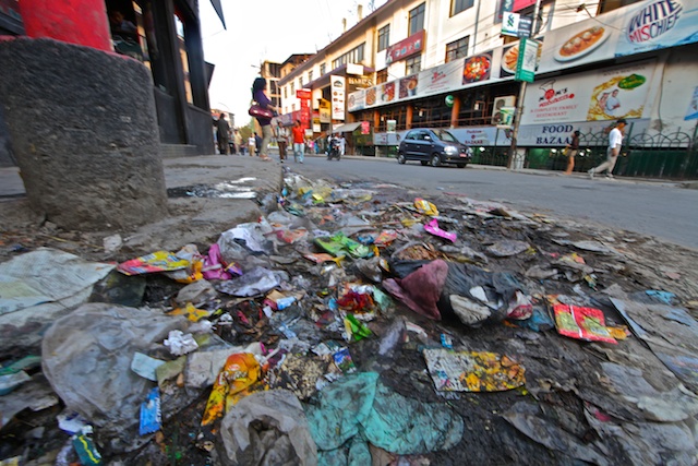 Trash Day Curbside Pile in Kathmandu, Flattened by Rush-Hour Traffic
